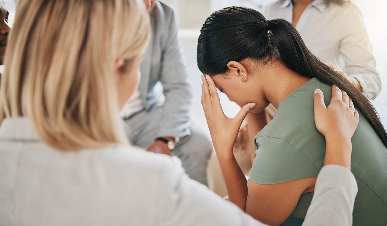 Grief, loss and woman at community support group for mental health, counseling or help. Solidarity, trust and group of people in circle comforting, helping and supporting lady with bad news together.