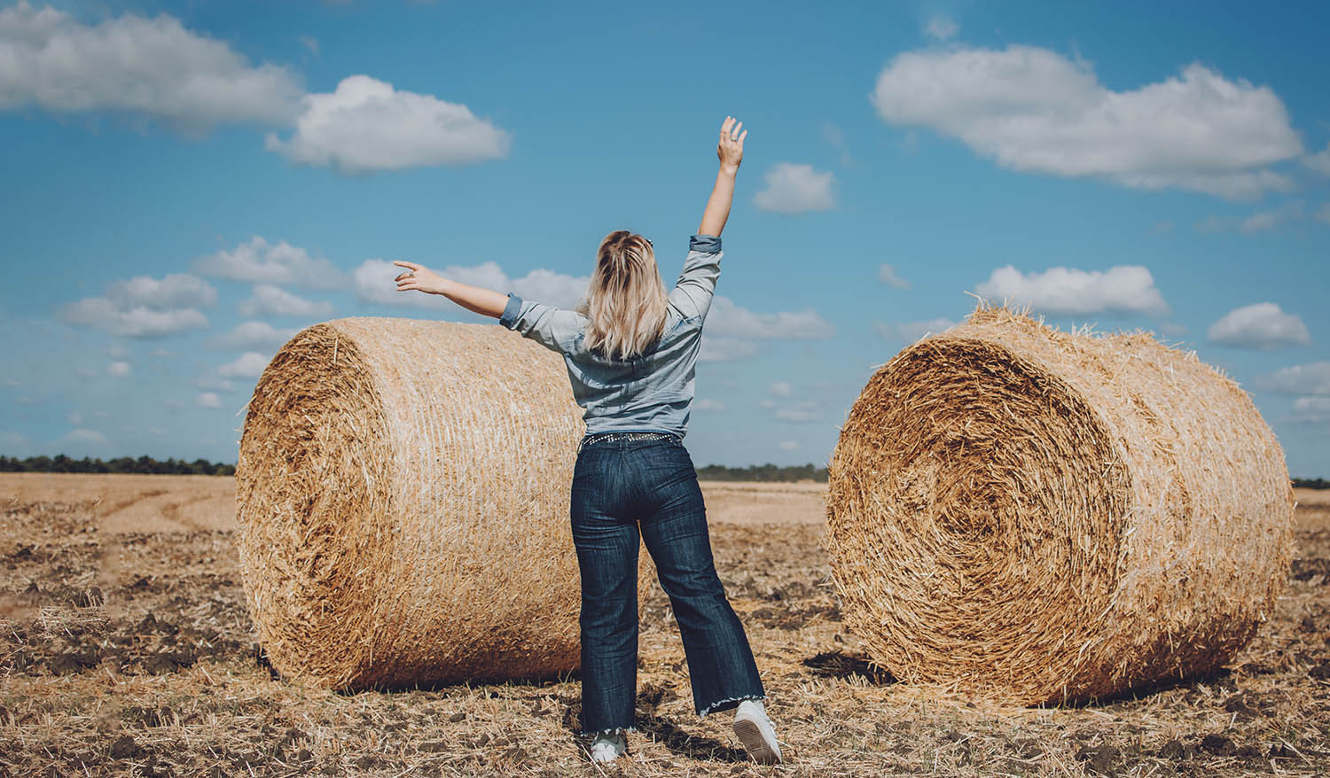 Beautiful girl near hay bales in the countryside. girl on the background of haystacks